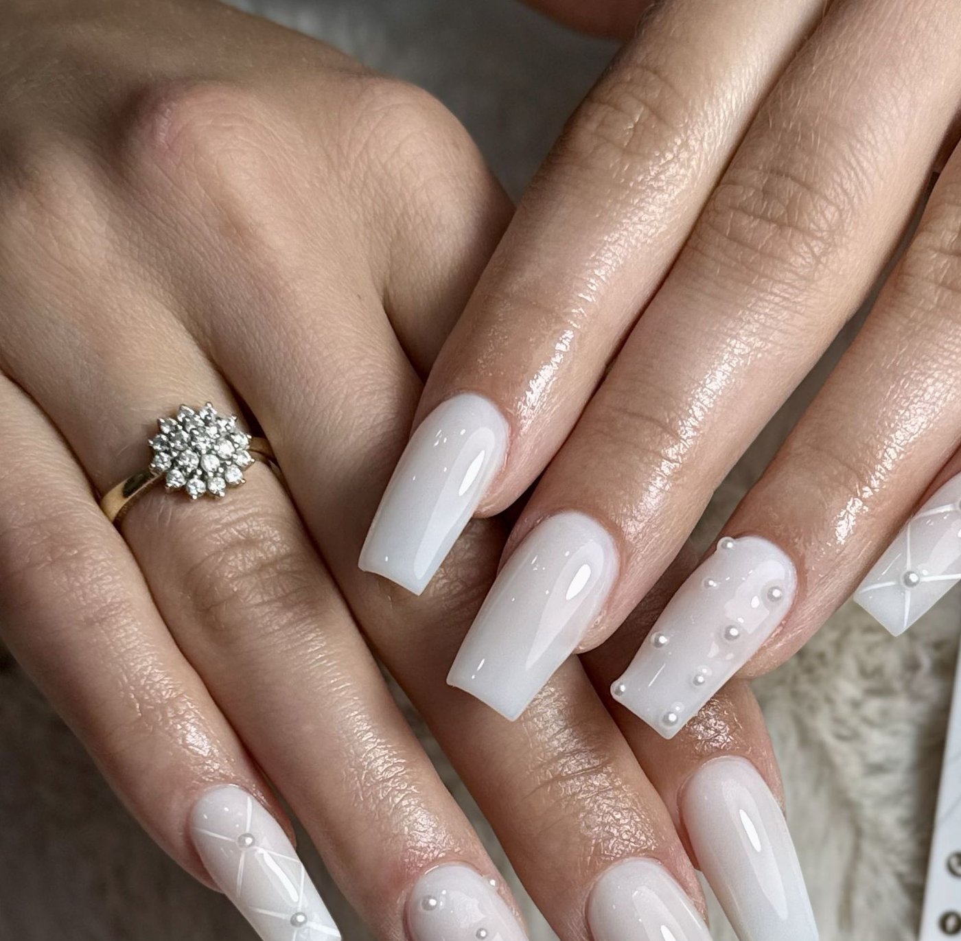 Elegancki manicure w kolorze mlecznego beżu z perłowymi zdobieniami